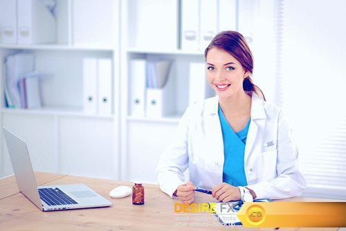 Beautiful young smiling female doctor sitting at the desk - 21 UHQ JPEG