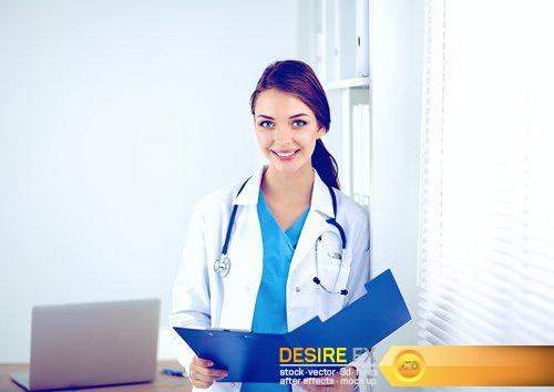 Beautiful young smiling female doctor sitting at the desk - 21 UHQ JPEG